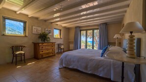 Une chambre à coucher avec un grand lit, une commode en bois et une fenêtre donnant sur l’extérieur.