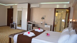 Una habitación de hotel con una cama grande, un armario, un escritorio y un espejo.