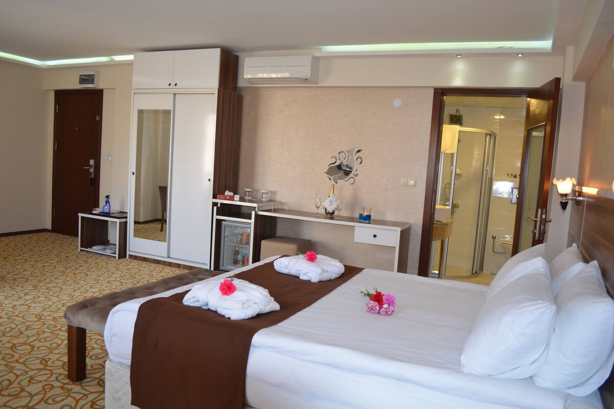 Una habitación de hotel con una cama grande, un armario, un escritorio y un espejo.