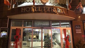 Exterior del Hotel Perana con un árbol de Navidad y decoraciones rojas.