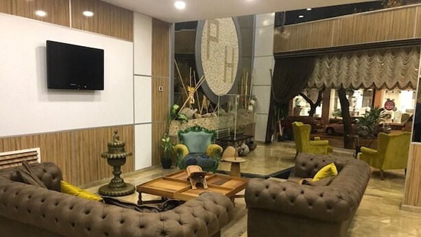 Un vestíbulo amplio con un gran conjunto de sofás, una mesa de centro y un televisor instalado en la pared.