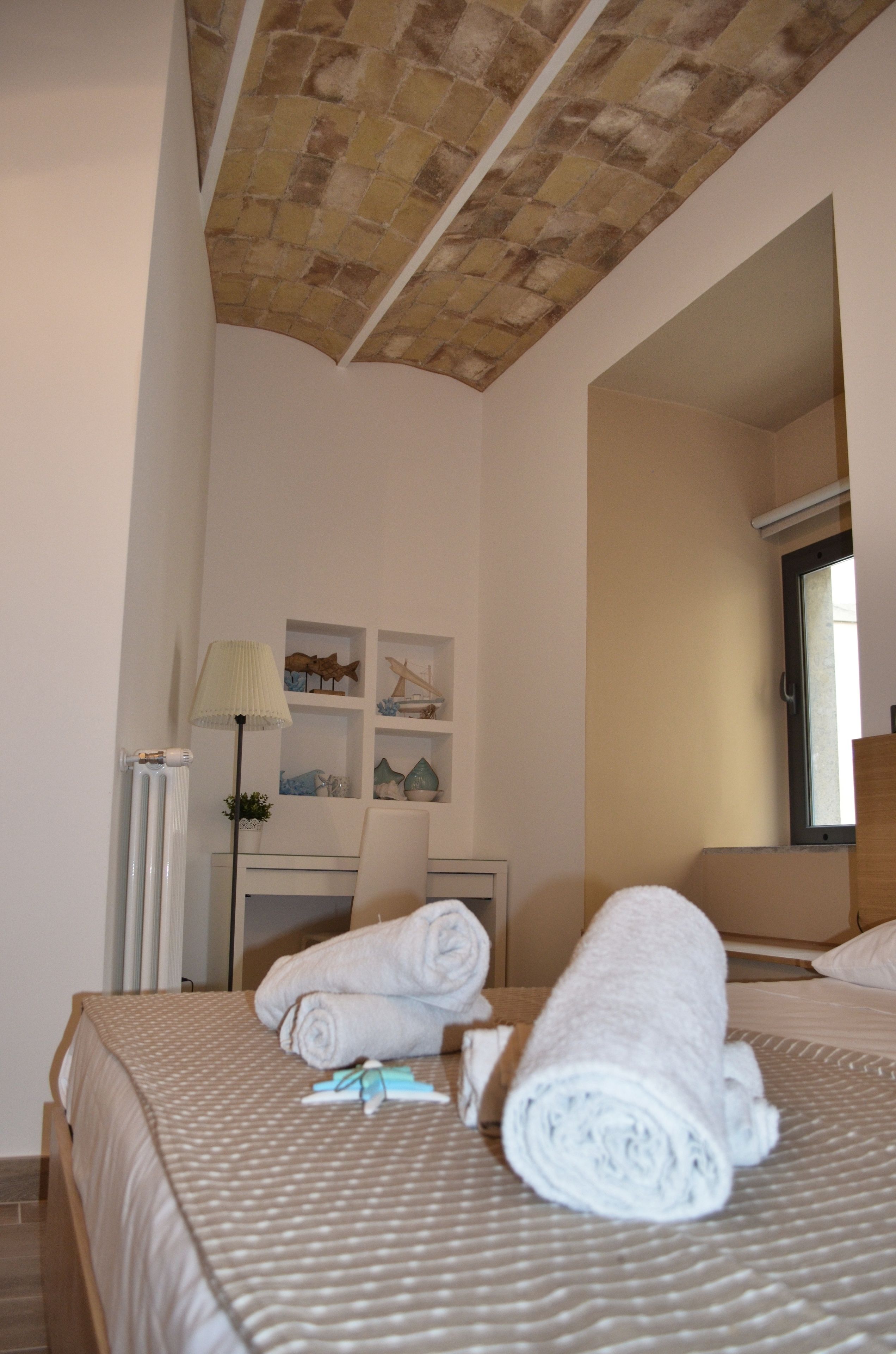 Una habitación de hotel con una cama, un escritorio, una lámpara y una ventana.