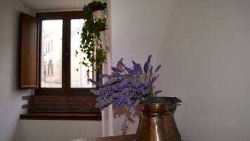 A room with a window, a vase with lavender, and a hanging plant.