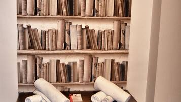 Une bibliothèque remplie de livres et deux serviettes enroulées posées sur un coffre en bois.