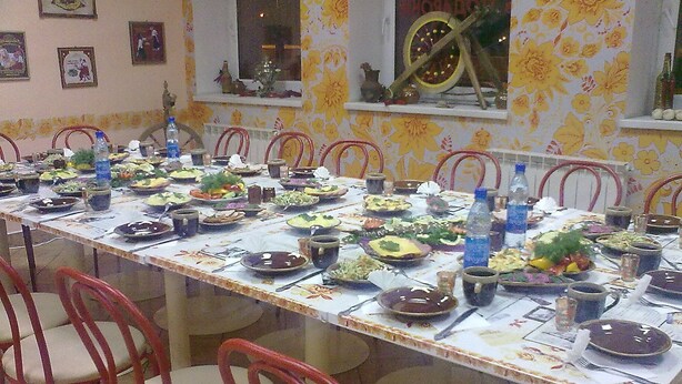 A long dining table set with plates, bowls, and bottles, surrounded by red chairs.