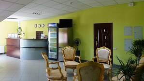 A reception area with a counter, a refrigerator, and three ornate chairs.
