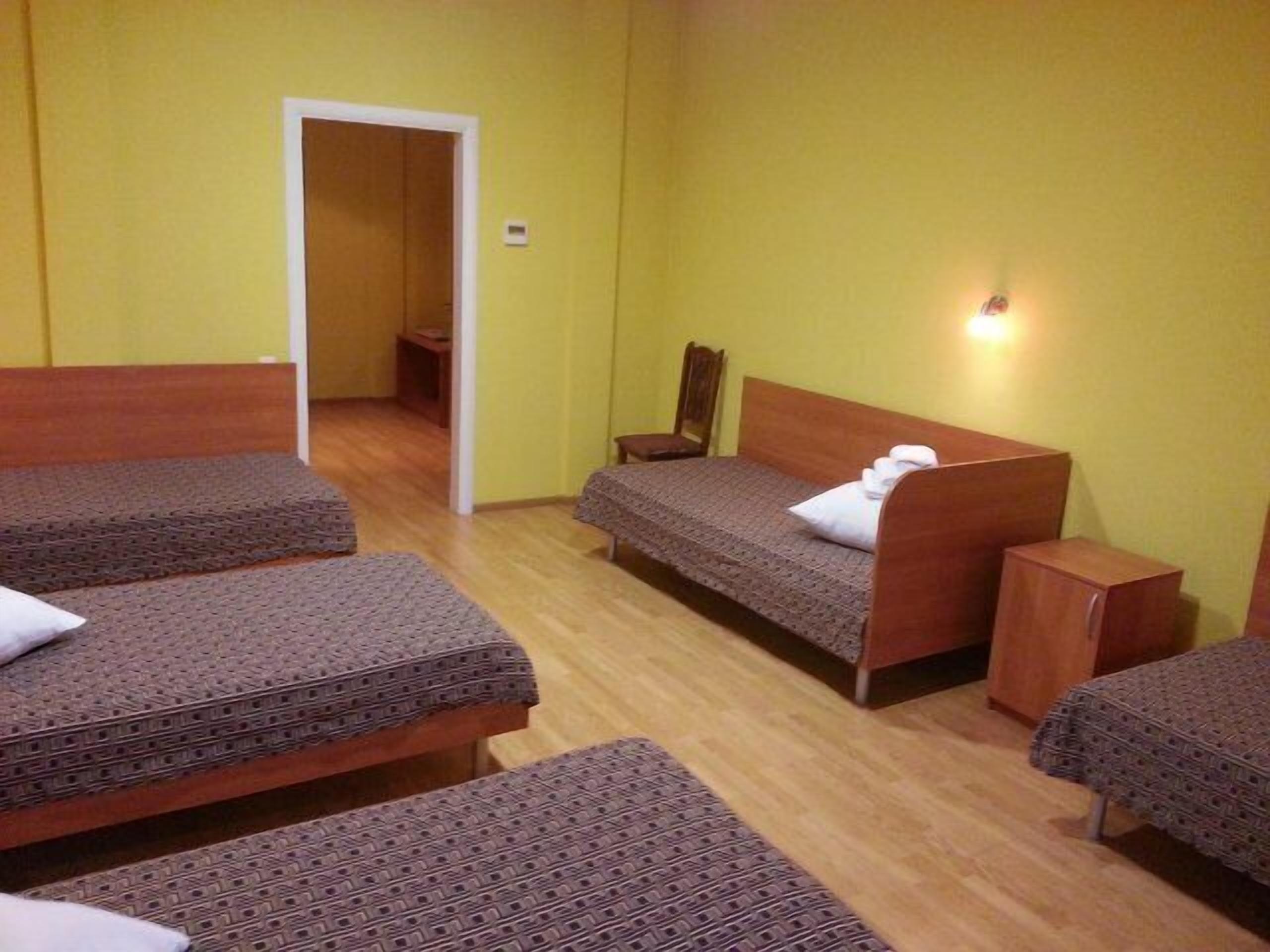A room with four beds, wooden headboards, and a small table.