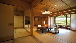 A traditional Japanese room with tatami flooring, a low table, and a television. - Kagetsutei (Shimoda)