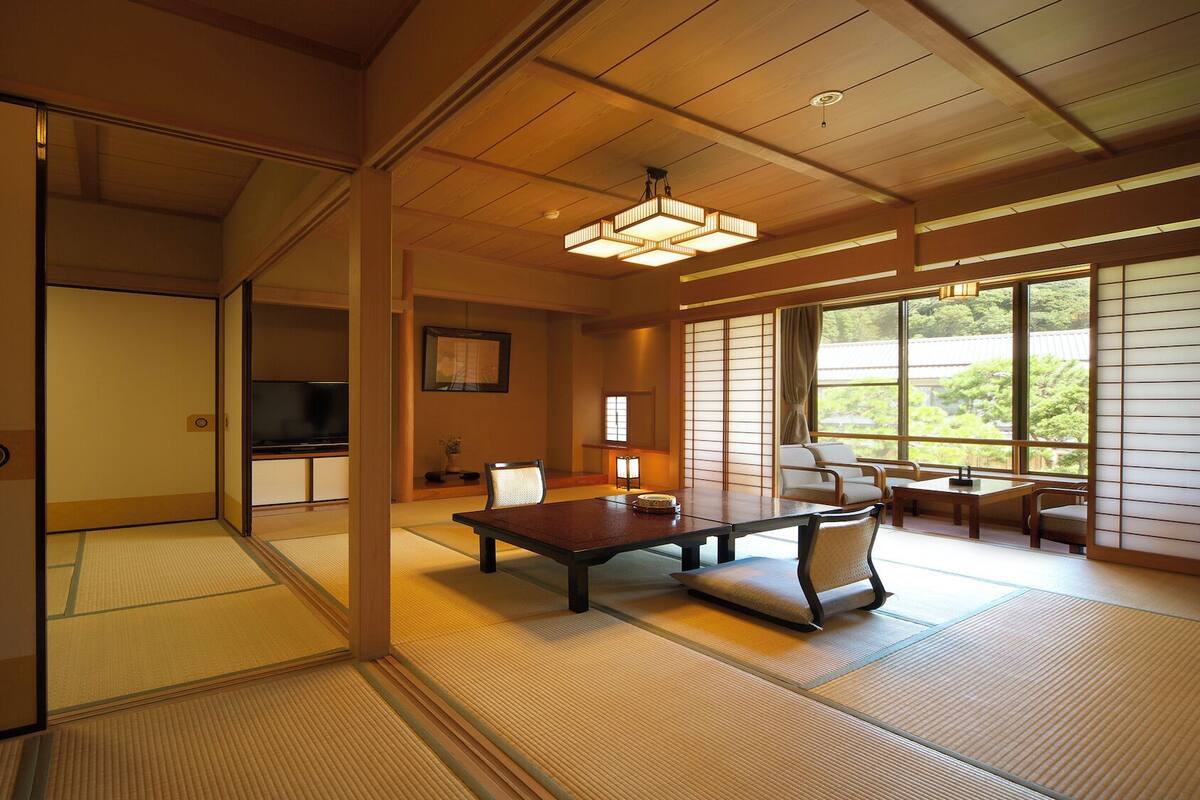 A traditional Japanese room with tatami flooring, a low table, and a television.