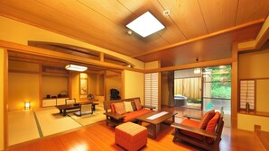 A traditional Japanese-style room with tatami flooring, a low wooden table, and a sofa with cushions. - Kagetsutei (Shimoda)
