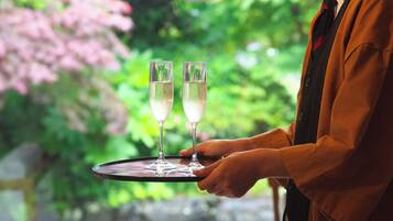 A person holding a tray with two glasses of champagne.