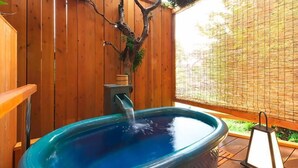 A hot tub in a wooden outdoor setting with a tree sculpture and a lantern. - Kagetsutei (Shimoda)