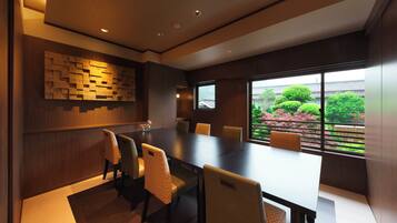 A modern conference room with a large table and chairs, wooden paneling, and a view of greenery outside.