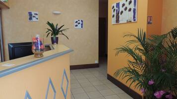 A reception area with a desk, potted plants, and artwork on the walls.