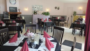 A restaurant with tables set for dining, a clock on the wall, and a menu board. - Le Gue De Genes (Ambrières-les-Vallées)