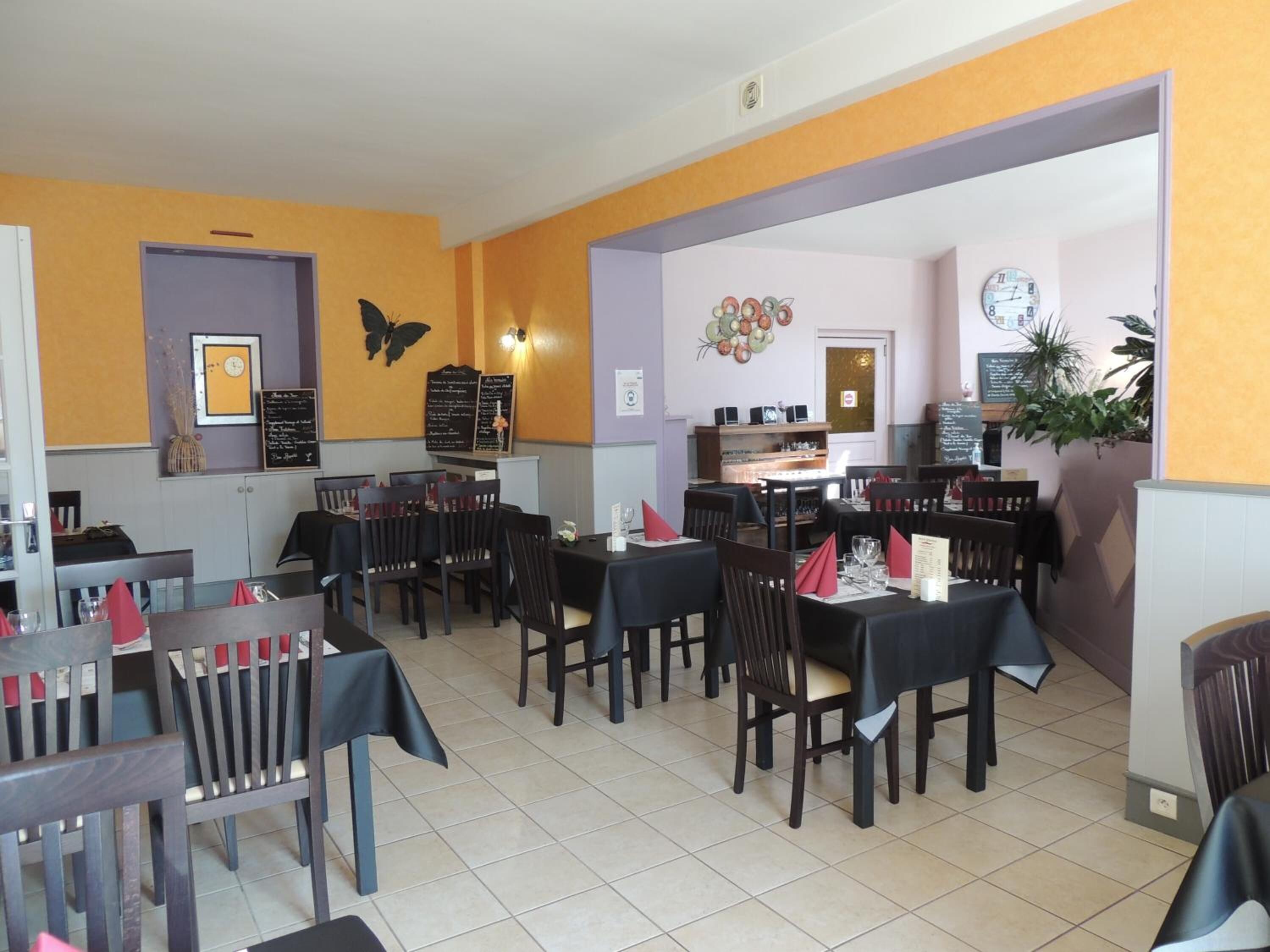 A restaurant with multiple tables and chairs, a menu board, and wall decorations including a butterfly and a clock.