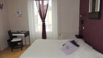 A bedroom with a bed, a desk, and a chair.