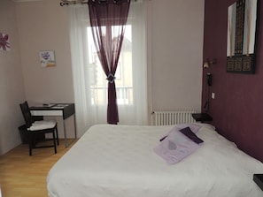 Een slaapkamer met een bed, een bureau en een stoel.