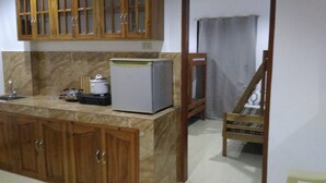 A kitchen with wooden cabinets, a refrigerator, a sink, and a chair. - Sealor Pension House (Puerto Princesa)