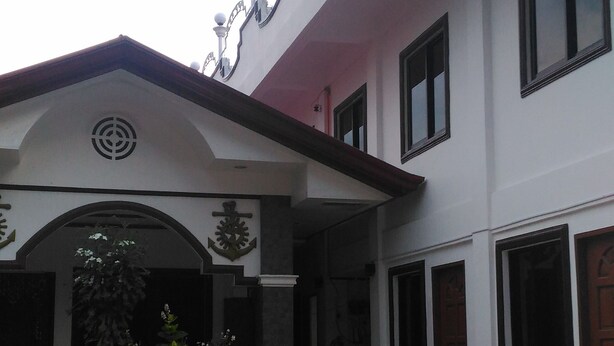 A two-story building with a covered entrance, a balcony with railings, and a small garden area. - Sealor Pension House (Puerto Princesa)