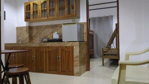 A kitchen with wooden cabinets, a marble countertop, a refrigerator, and a chair. - Sealor Pension House (Puerto Princesa)