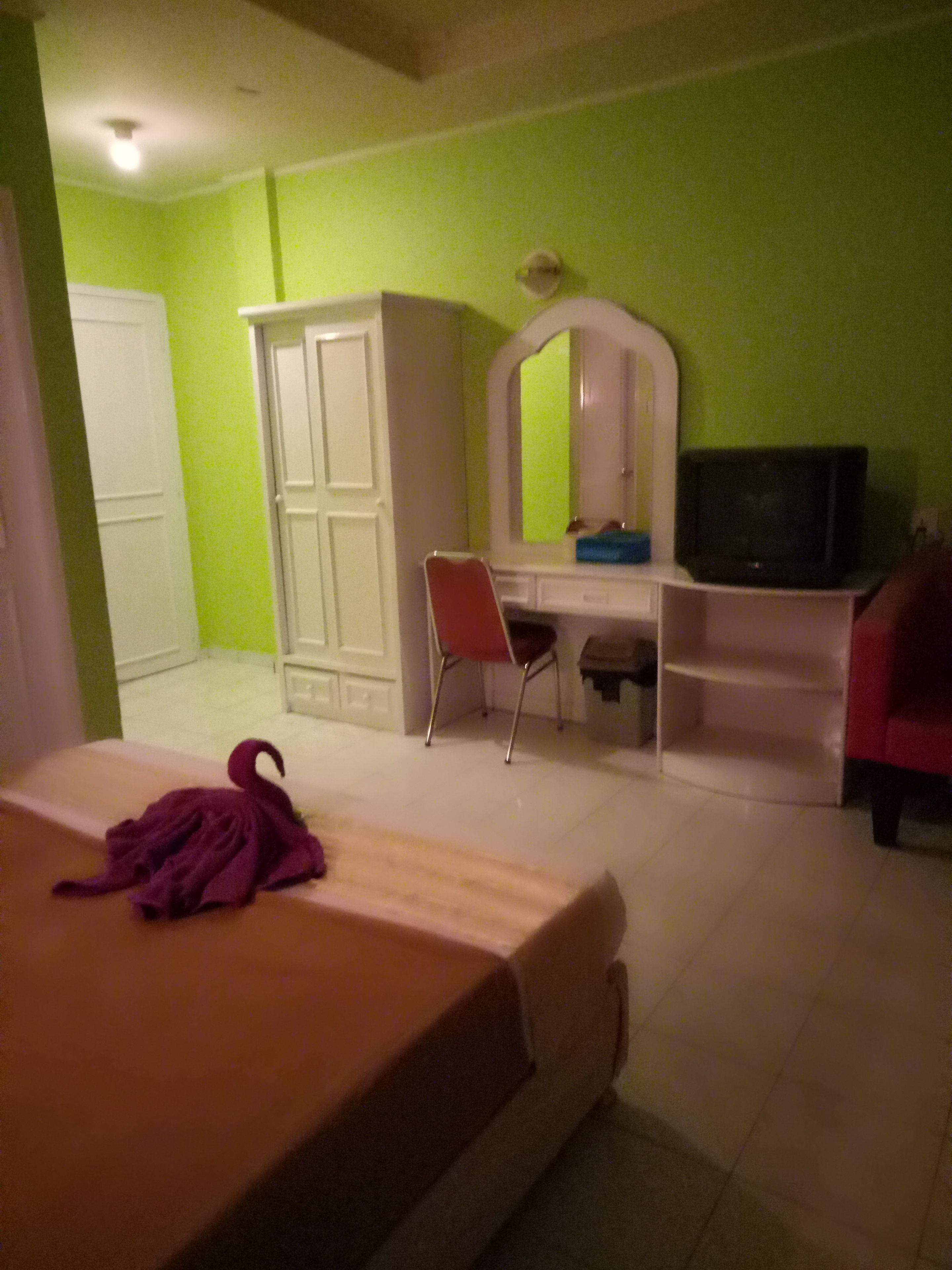 A bedroom with a bed, a desk with a chair, a wardrobe, and a television.