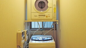 Een compact wasmachine-droogcombinatie in een kleine wasruimte met een raam.