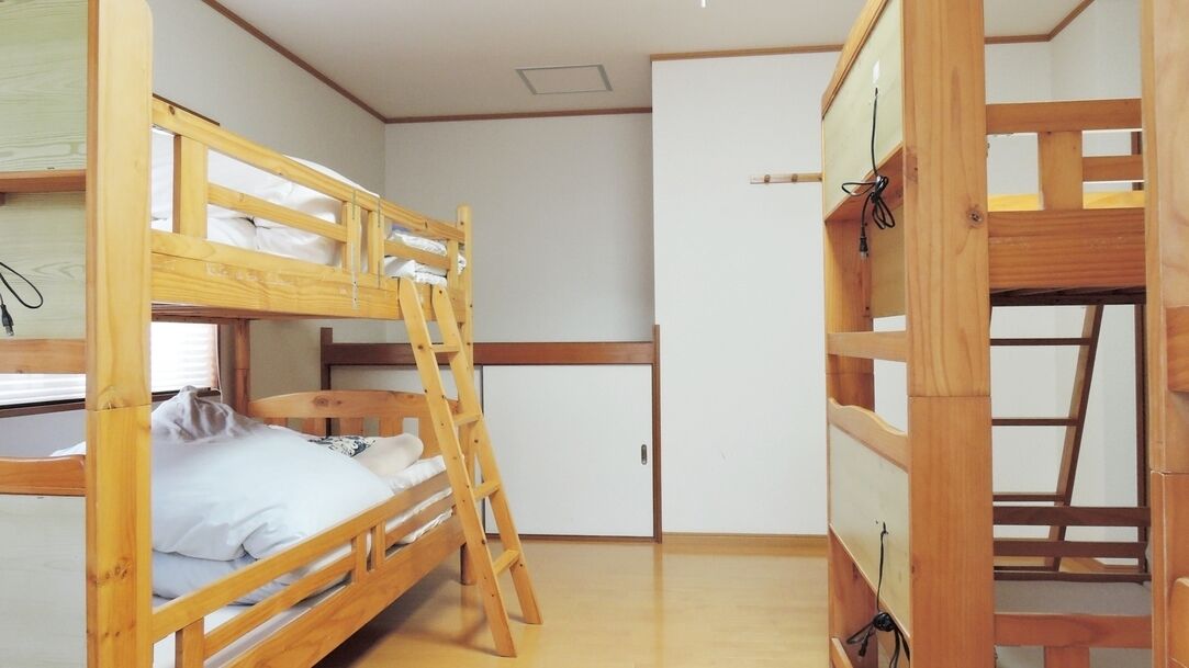 Een slaapkamer met een stapelbed, een kledingkast en een bureau.