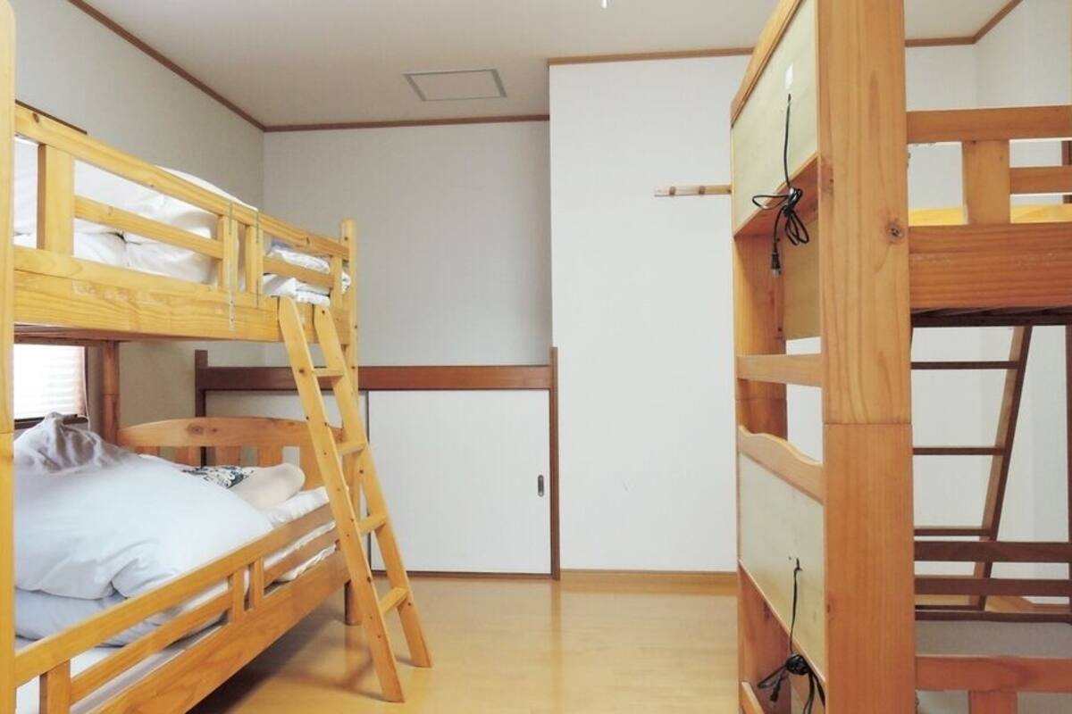Ein Schlafraum mit Etagenbetten, einer Leiter, einem Kleiderschrank und einem Schreibtisch.