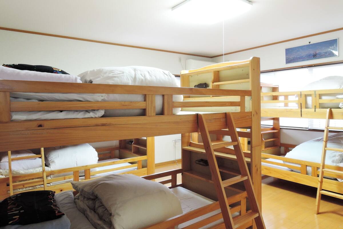 Ein Schlafsaalzimmer mit Etagenbetten, Holzmöbeln und einer Deckenleuchte.