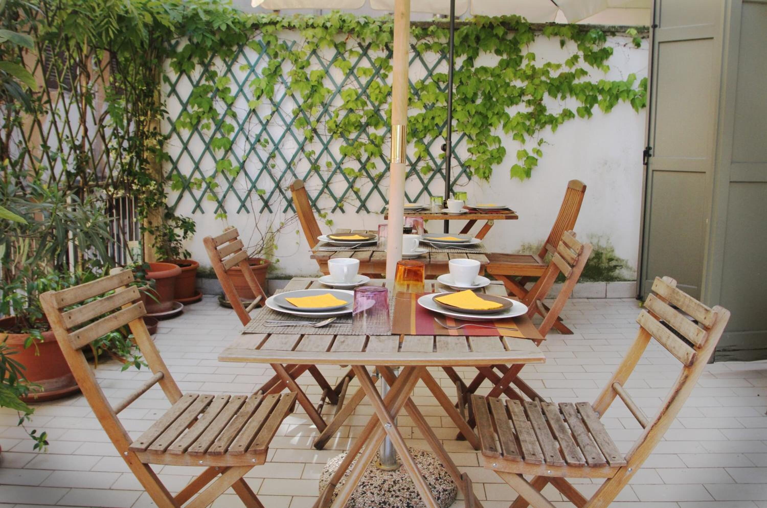 A wooden table set with plates, cups, and a small vase.