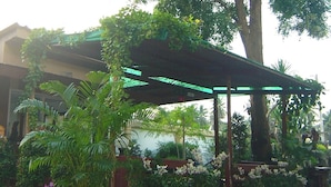 A covered outdoor area with potted plants and a pergola structure. - Coconut Home Resort (Bang Khonthi)