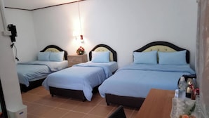A hotel room with three single beds, a wooden desk, and a small table with a vase of flowers. - Coconut Home Resort (Bang Khonthi)