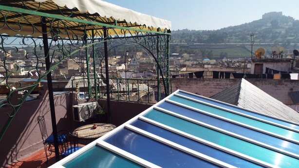 A rooftop terrace with blue glass panels and a metal pergola. - Maison Adam (Fes)