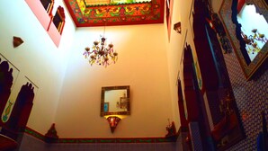 A room with a chandelier, a mirror, and ornate wall decorations. - Maison Adam (Fes)