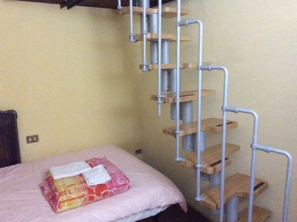 A room with a bed, a metal ladder, and a wooden shelf unit. - Antico Borgo Toscano (Montecatini Terme)