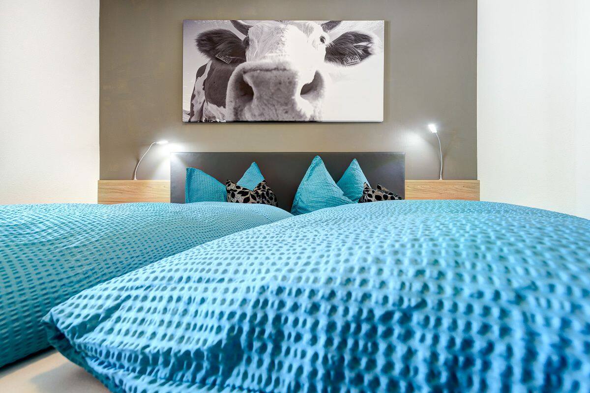 A bedroom with a bed, a headboard, and a wall-mounted picture.