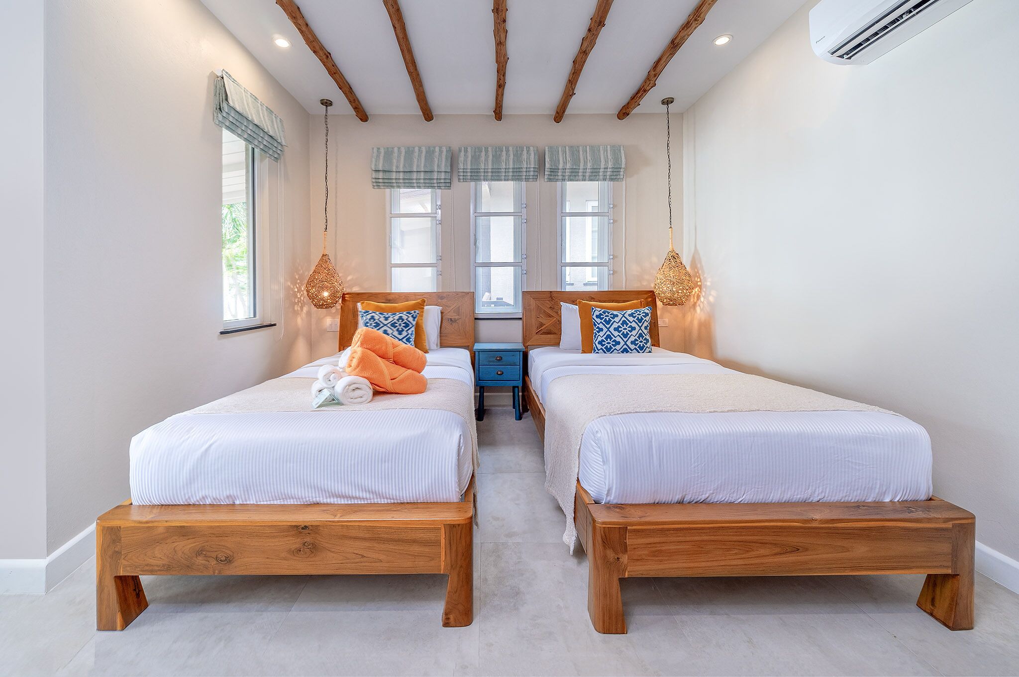 A bedroom with two wooden beds, a nightstand, and a hanging light fixture.