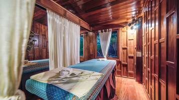 A wooden room with a bed, curtains, and a view of the outdoors.