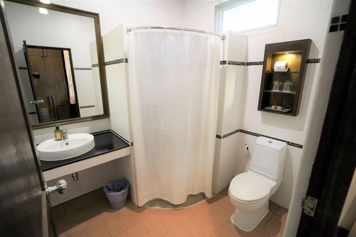 A bathroom with a white sink, a toilet, a shower curtain, and a mirror.