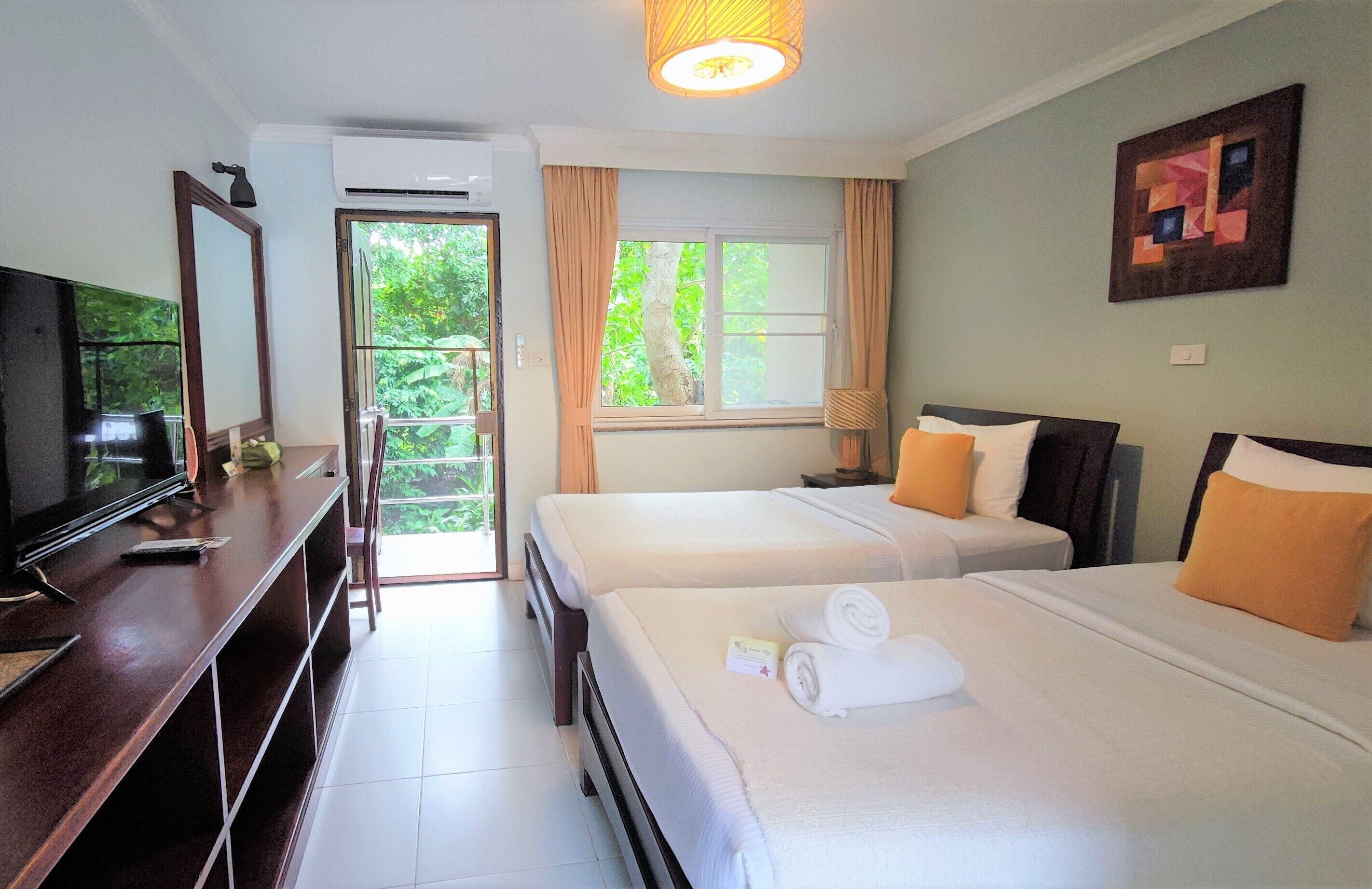 A hotel room with two beds, a TV, a desk, and a window with curtains.