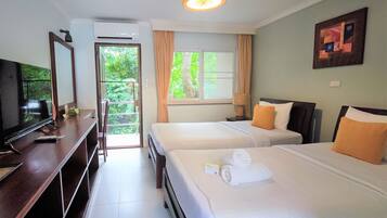 A hotel room with two beds, a TV, a desk, and a window with curtains.