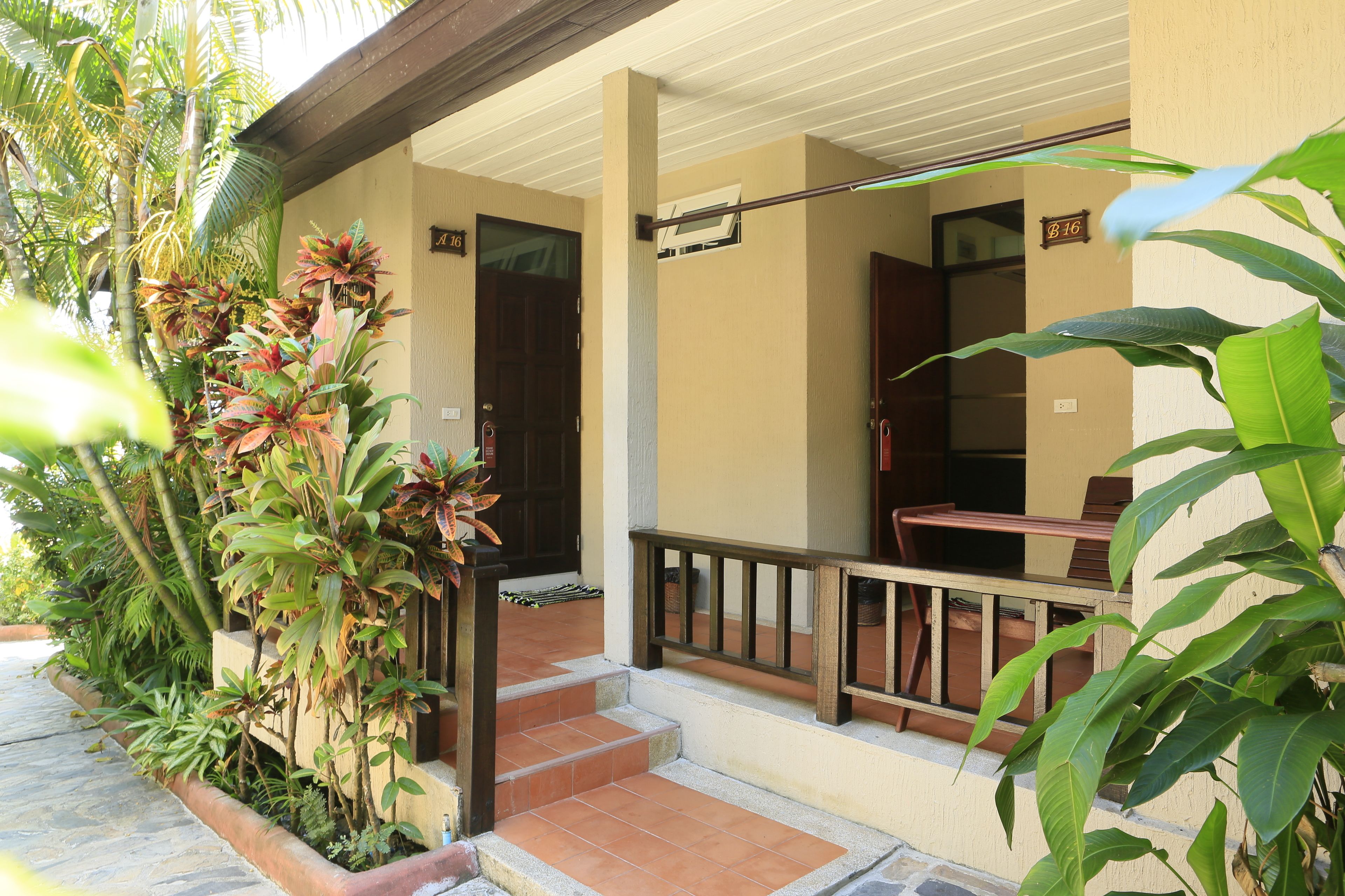 A hotel entrance with a covered porch, steps leading to the door, and a sign indicating room number 16.
