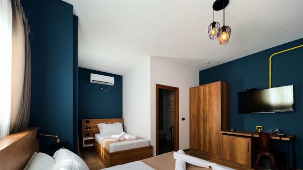A hotel room with a bed, a desk, a TV, and an air conditioning unit. - Oda Hotel Tirana (Tirana)