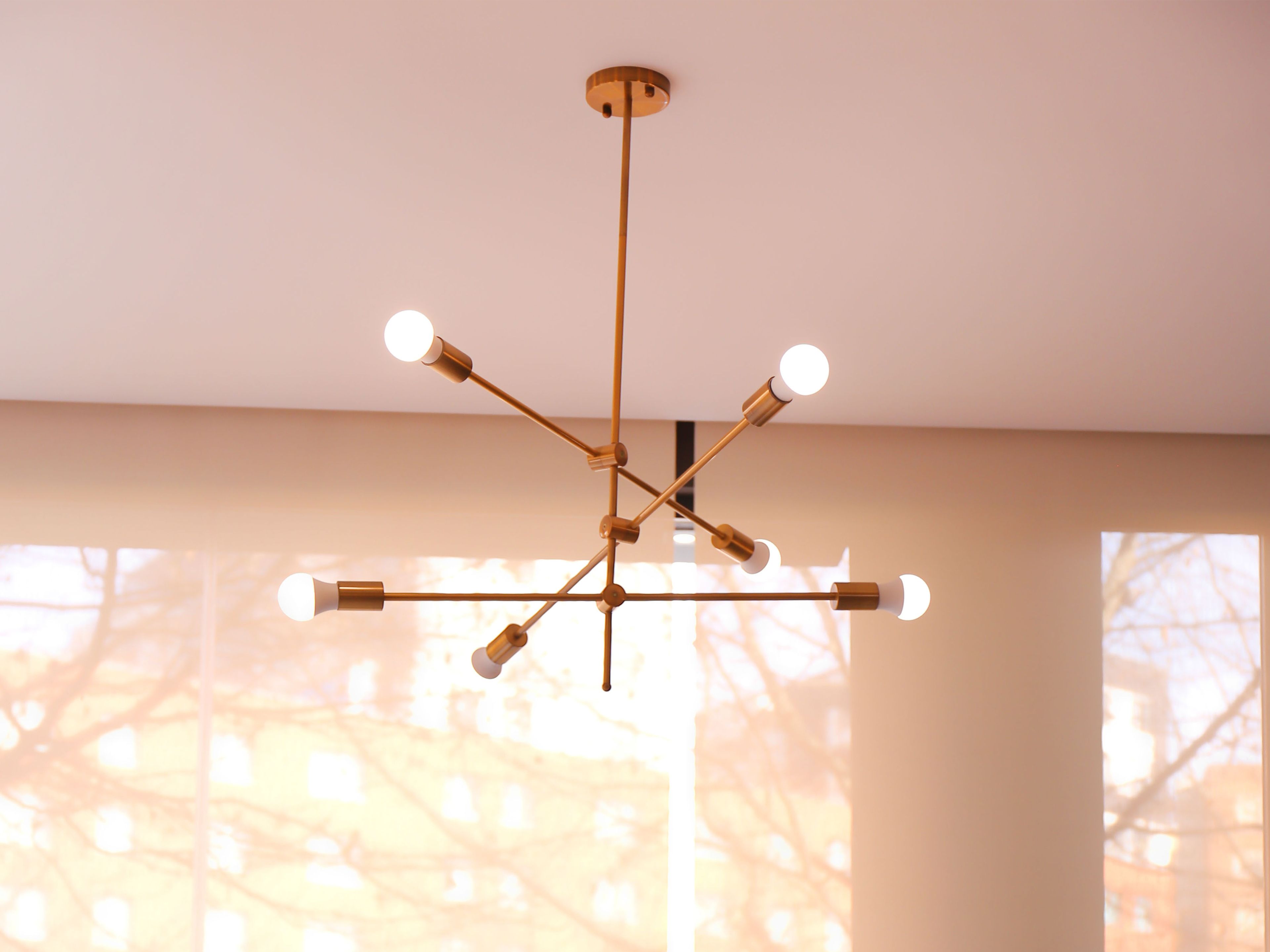 A chandelier with multiple light fixtures in a room with large windows.