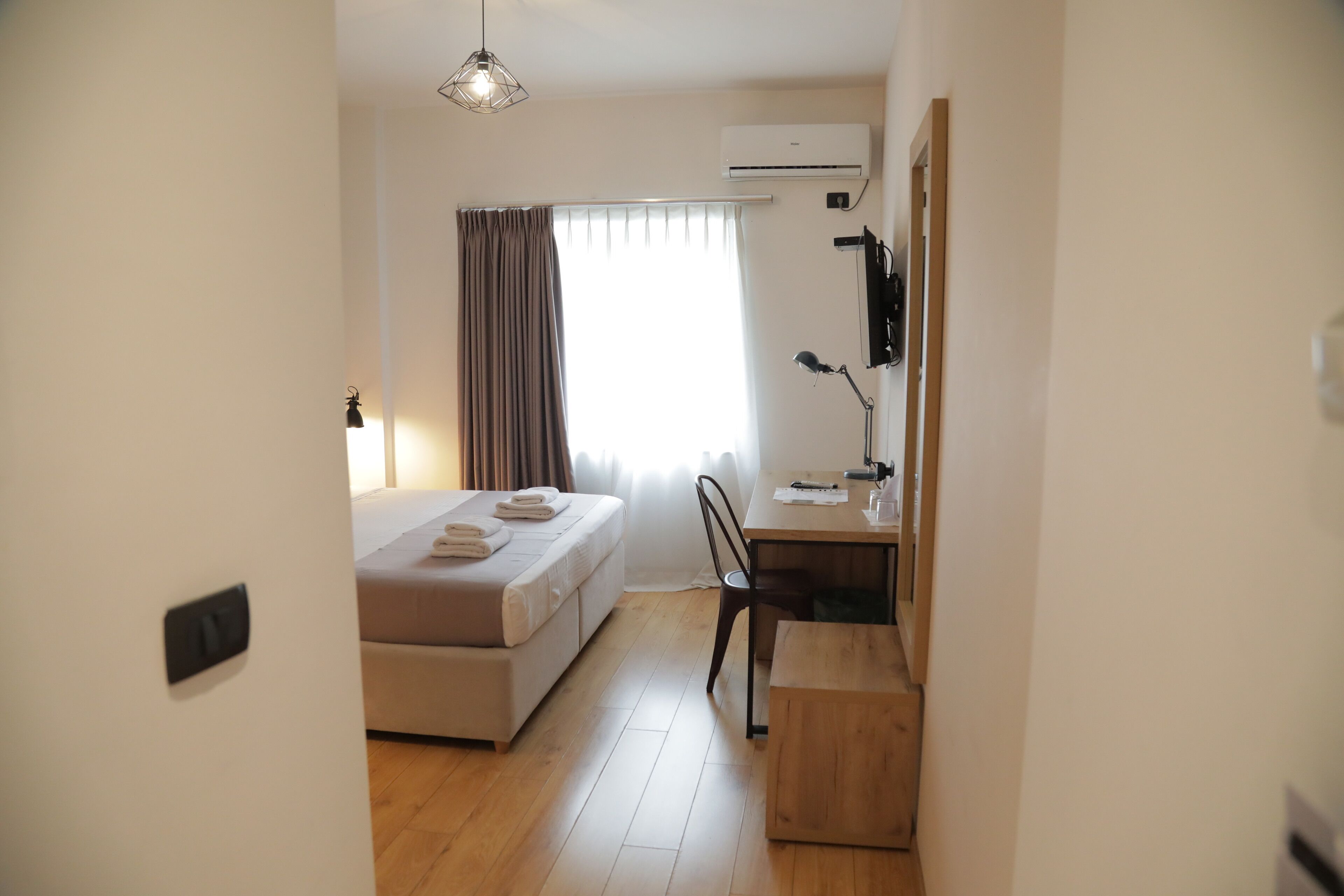 A modern hotel room with a bed, a desk, and a chair.