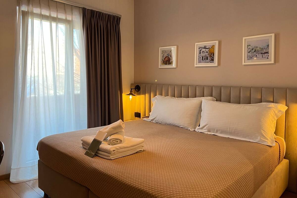A neatly made bed with a folded towel and a tag, a bedside lamp, and three framed pictures on the wall.