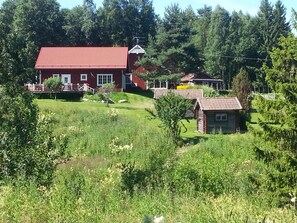 A red house with a tiled roof, surrounded by greenery and trees. - Kullsbjörkens Bed & Breakfast (Tallberg)