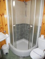 Un baño con cabina de ducha, inodoro y lavamanos.