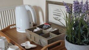 A wooden tray with a white kettle, a tea box, and a remote control on a table. - Valhalla B&B (Alexandria)